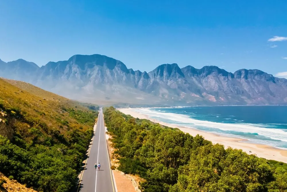Coastal road running alongside a beach with mountains in the background